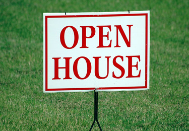 An open house sign against a green lawn.
